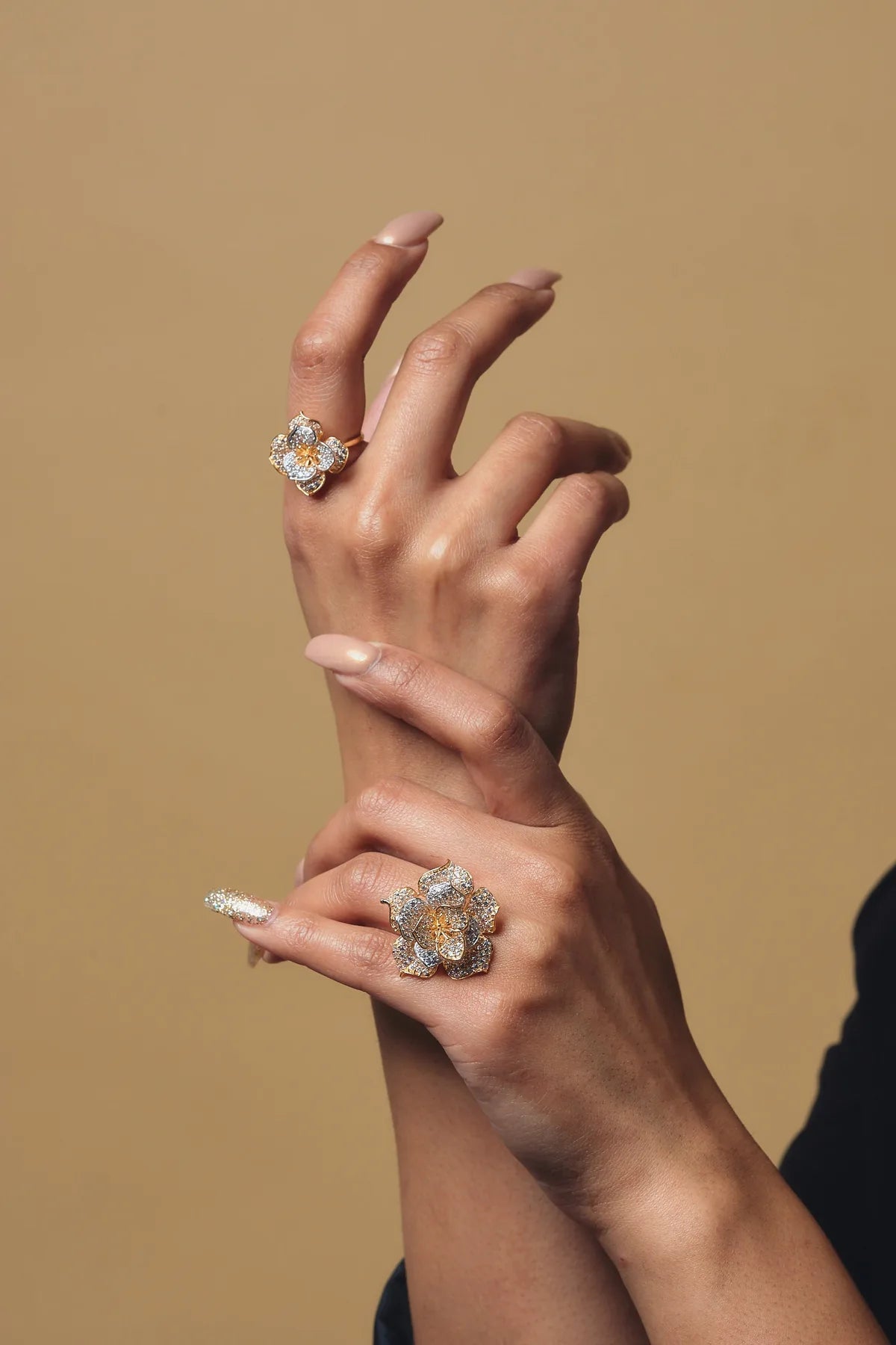 Hands wearing 22K gold floral diamond rings by Omar Jewelers